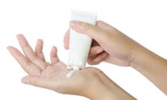 Young woman applying hand cream on white background