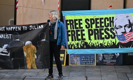 A woman holds a protest sign outside the building.