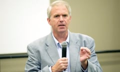 White man in gray suit talking into a microphone