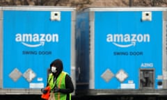 A worker in a face mask walks by trucks parked at an Amazon facility as the global coronavirus outbreak continued in Bethpage on Long Island in New York, U.S., March 17, 2020. REUTERS/Andrew Kelly