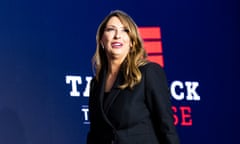 Woman in black suit stands in front of graphic