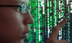 A young man looking at computer code which is reflecting in his glasses