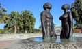 A large scale sculpture shows a man and woman looking to the sky and emerging from the water