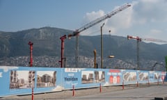 A view of Antakya with new fencing displaying architectural plans of the reconstruction from the earthquake damage while cranes operate in the background.