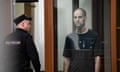 Wall Street Journal reporter Evan Gershkovich stands listening to the verdict in a glass cage of a courtroom