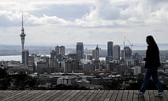 Person walks in front of views of the Auckland skyline and habour