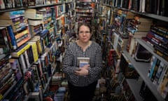 Rebecca Sharrock standing between two rows of shelves densely packed with books