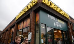 Shoppers walk past a branch of Morrisons.