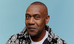 Lenny Henry wearing a patterned black and white shirt in front of a blue background.