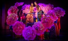 Actors on stage surrounded by dancers with flower fans