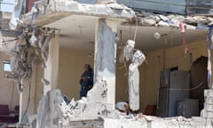 A Palestinian woman looks on from a house that was destroyed in an Israeli strike