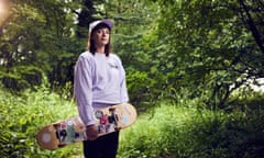 Marianne Eloise stands in a field and holds a skateboard