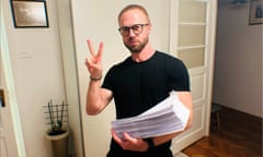 Andrei Gnyot gives a V for victory sign with one hand as he holds papers in the other