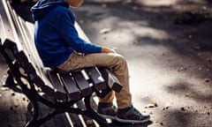 Lone boy sitting on bench, looking downcast