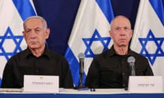 Benjamin Netanyahu and Yoav Gallant seated in front of Israeli flags during a press conference