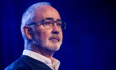 A man wearing glasses and collared shirt looks ahead