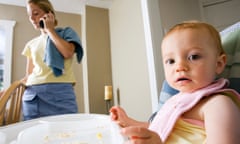 Baby girl (18-21 months) sitting in highchair, mother on mobile phone