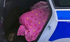 someone under a duvet in the back of a police car