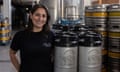 A young woman in a black T-shirt stands smiling among the barrels with vats in the background