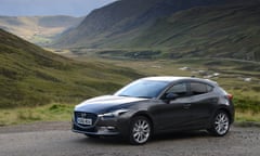 Mazda 3 2.0 parked in front of mountain scenery