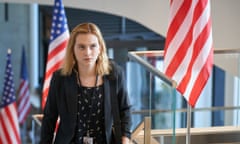 woman in a blazer walking up steps with american flags behind her