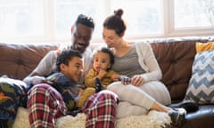 Multi-ethnic young family relaxing in pajamas on living room sofa<br>Happy family