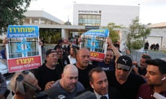 Right-wing activists cheering in front of armed and masked Israeli reservists from the 100 force wave Israeli flags while holding placards saying: 'The hero soldiers should be released. The conception generals and Military Advocate General should be detained'.