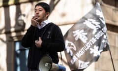 Hui stands on a stage and speaks into a megaphone