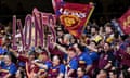Brisbane Lions fans cheer and wave flags in the stands during an AFL game