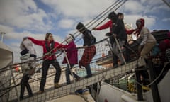 Aid workers help refugees and migrants to disembark a rescue vessel in Sicily, Italy. 