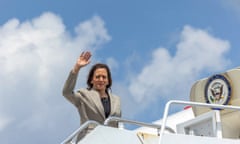 Kamala Harris waves from the top of stairs by an aircraft