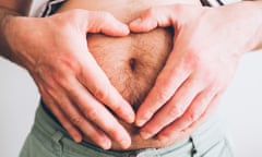 Man with his hands in a heart shape on his bare belly