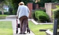 An elderly woman uses a mobility walker in a garden