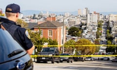 Man in navy uniform looks down street behind yellow caution tape