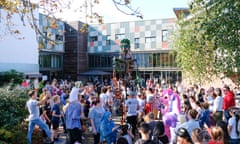 Adults and children (and two people dressed as unicorns) in a crowd round a large automaton puppet in the grounds of the Midland Arts Centre