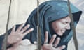 A mural showing a woman in a blue headscarf looking away and holding up her hands defensively.,