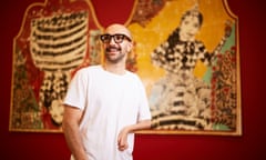 Mohammad Barrangi stands in a gallery showing his work. He is looking off to the side of the camera.