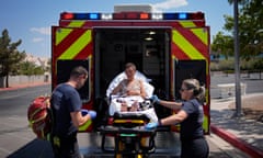 Firefighters help a woman into an ambulance for heat-related symptoms