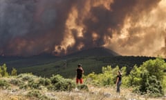 People watch wildfires burn near the village of Pournari, about 25km south-west of Athens, Greece. 