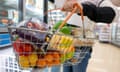 A woman holds a basket of groceries in a supermarket