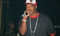 Black man wearing black shirt and white and red hat speaks into microphone