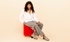 woman in white shirt and trousers sitting on a red box