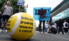 Protesters with a variety of props including a banner that reads 'Barclays blood money' and a giant tennis ball that reads 'Barclays sponsors Wimbledon and genocide'