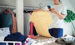 A woman takes a photo of T-shirt using her smartphone to sell her clothes