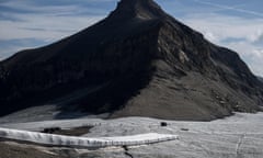 Hikers walk through the mountain pass which has very little snow between two completely barren mountains