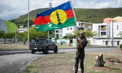 A pro-independence supporter waves a flag on the side of a road ahead of French parliamentary elections in Nouméa, New Caledonia
