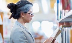 Older Hispanic woman reading book in library