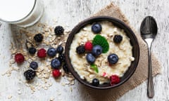 oatmeal porridge with fresh berries, glass of milk and spoon