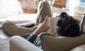 Mid adult man relaxing on sofa, reading book, rear view