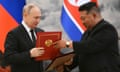 Putin and Kim hold a document in a red and gold folder